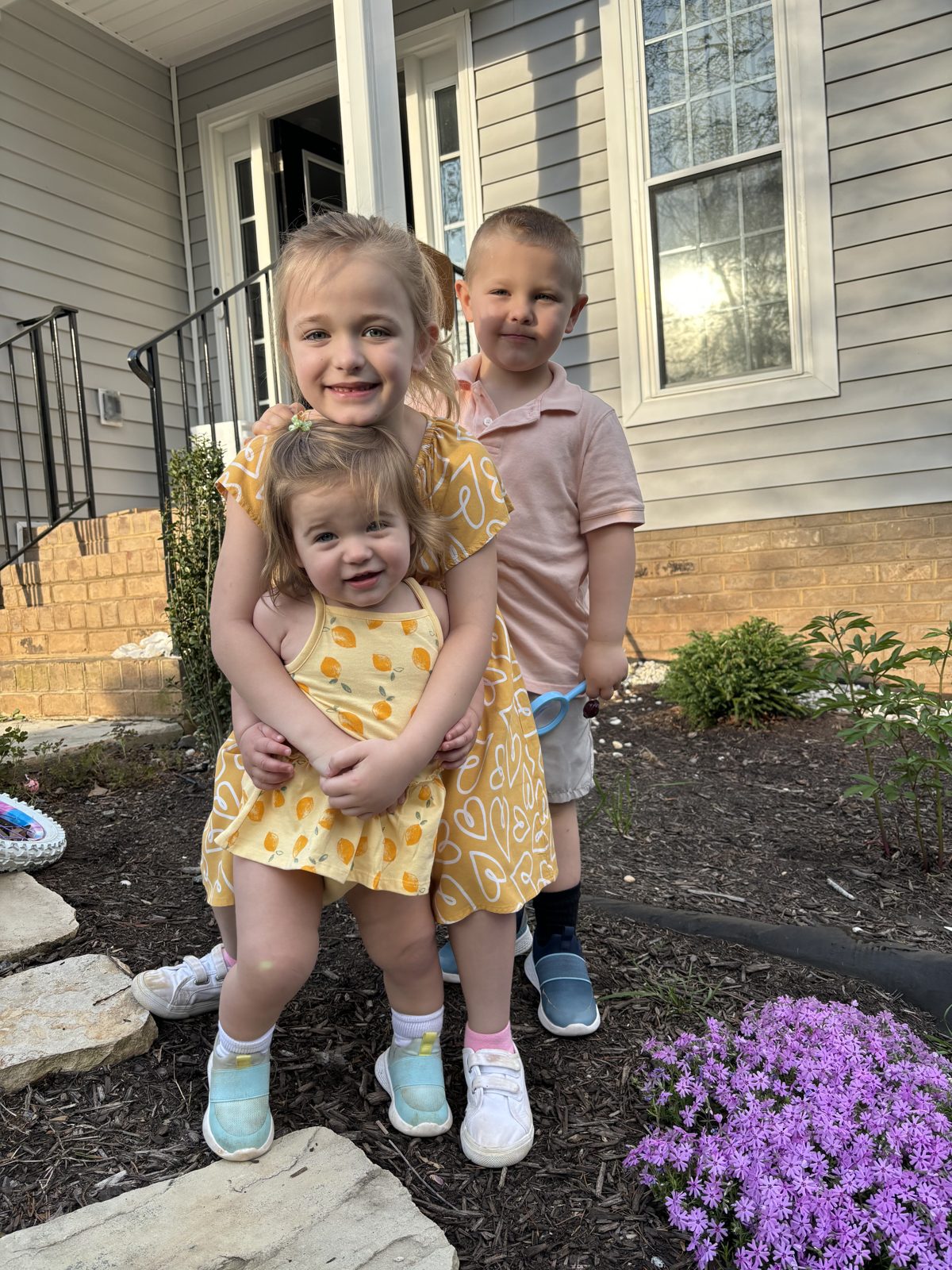 Three kids on the front steps in the spring